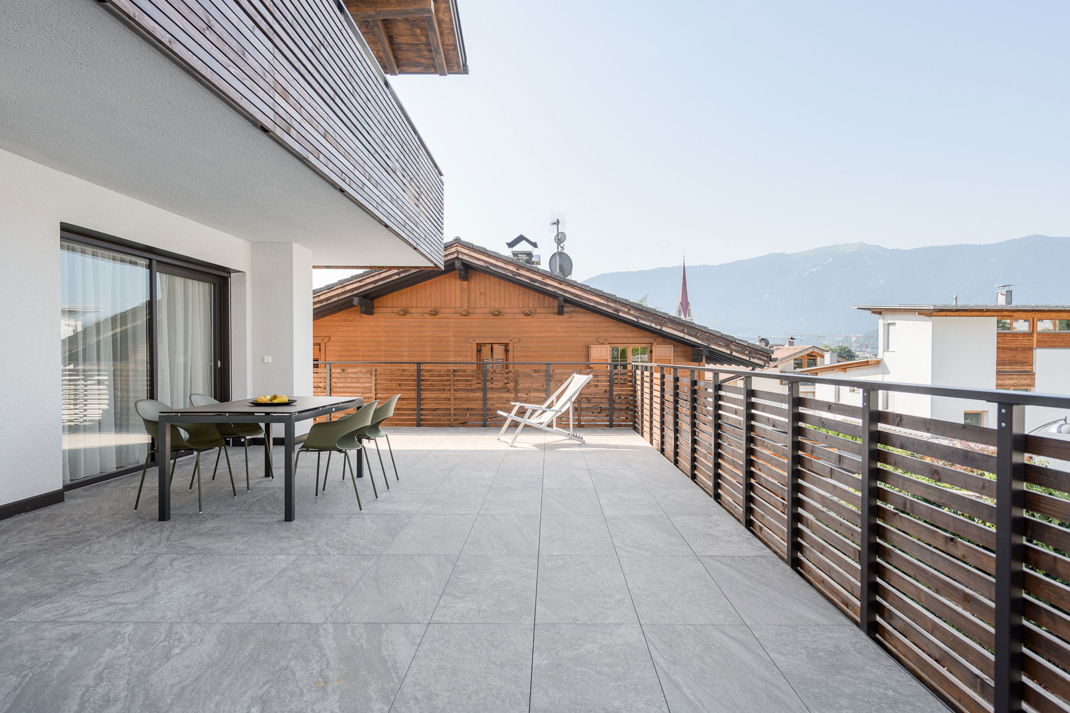 Large balcony with a table and four chairs and a deck chair