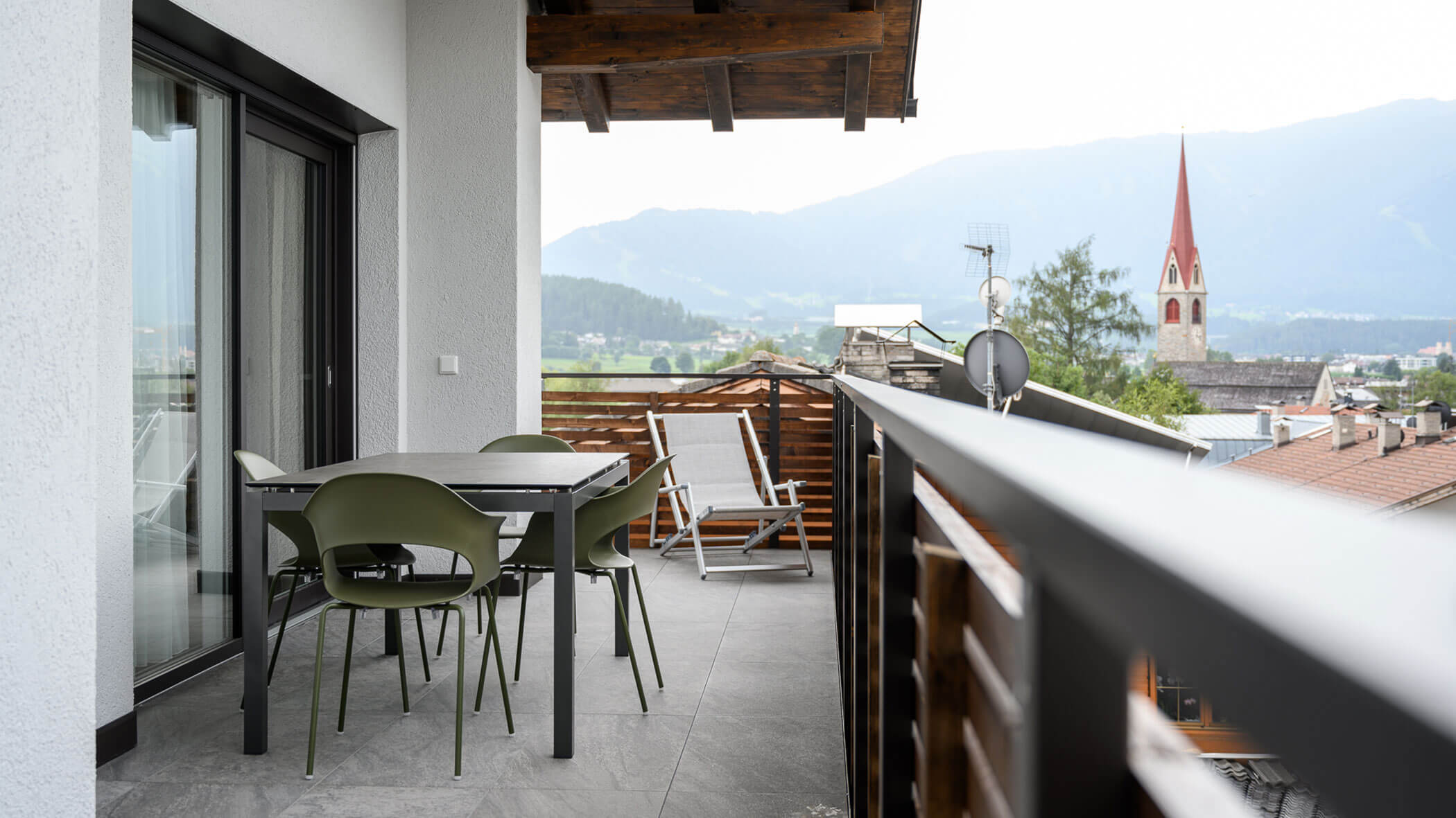 Large balcony with a table and chairs and a deckchair