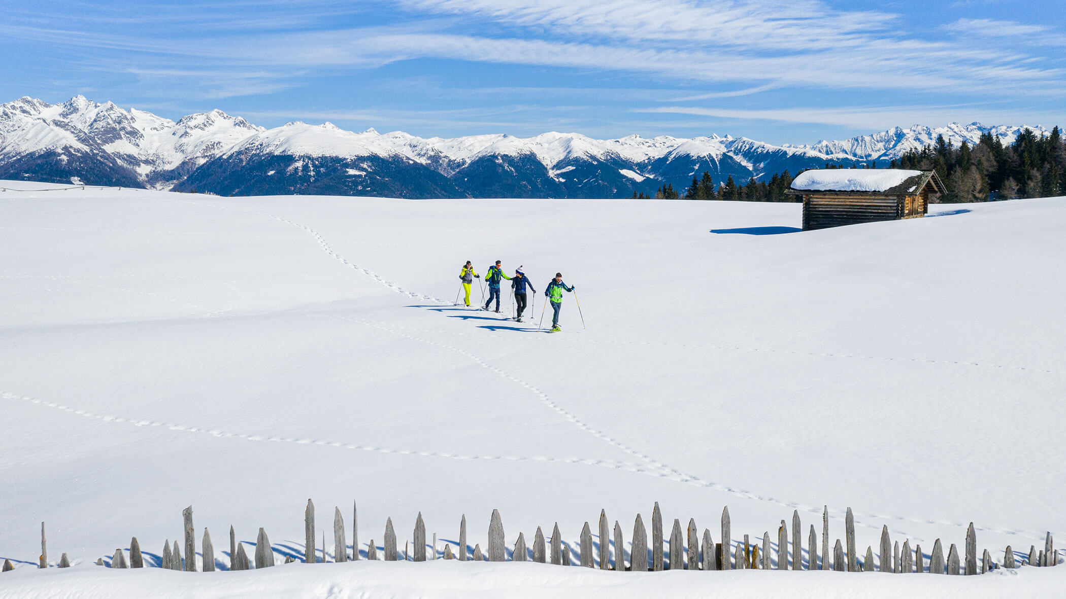 Four snowshoe hikers hiking across a snowfield