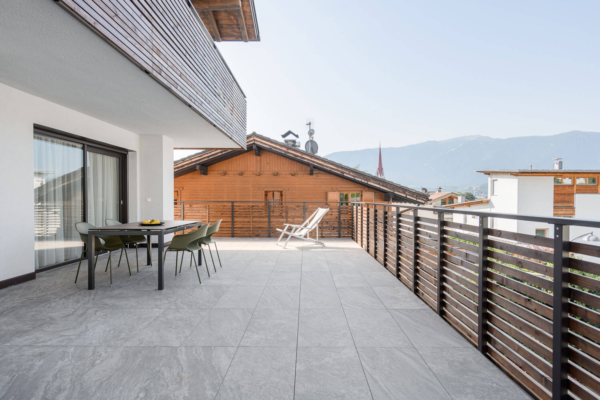 Large balcony with a table and four chairs as well as a sun lounger
