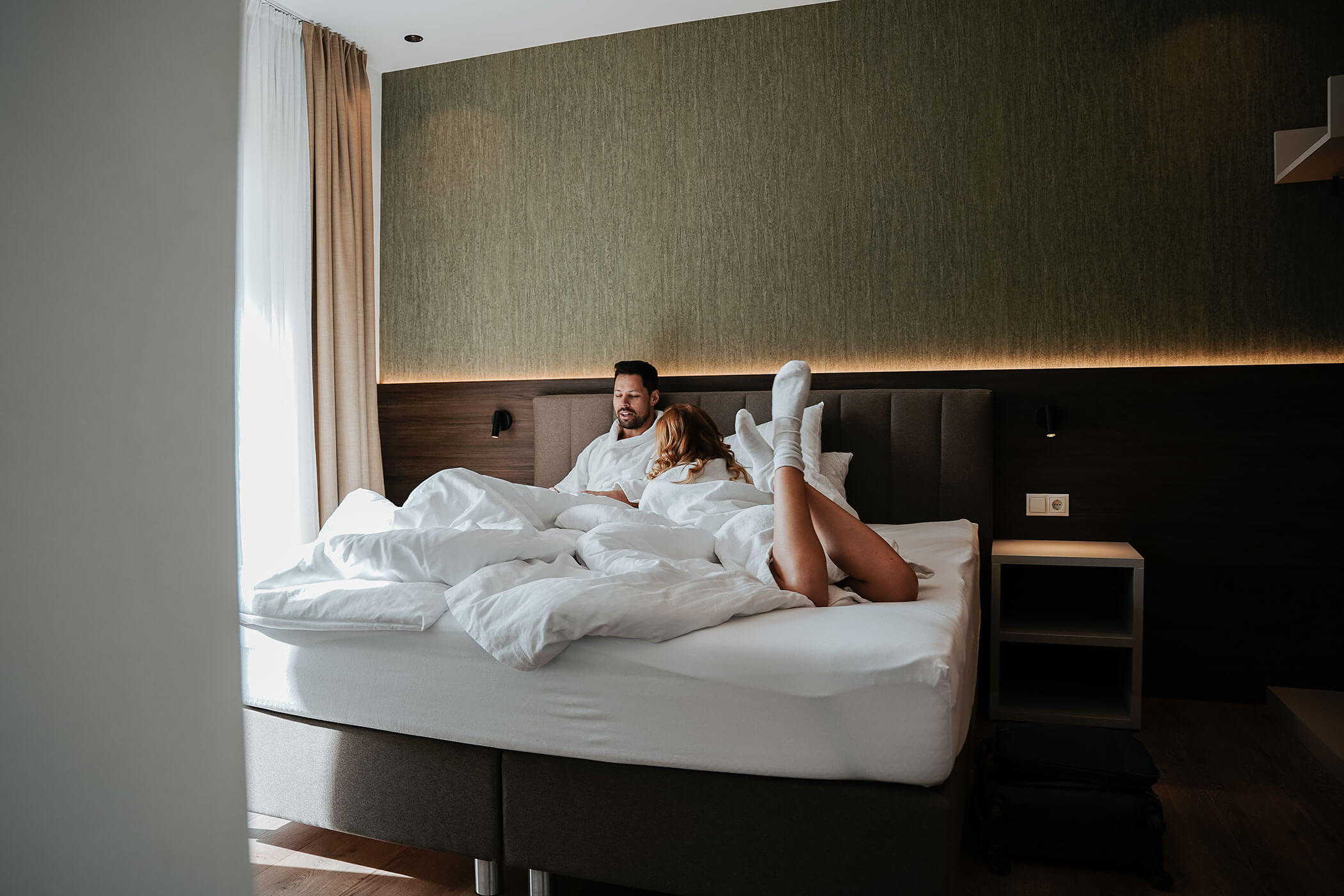 A couple lies in bed in their bathrobes